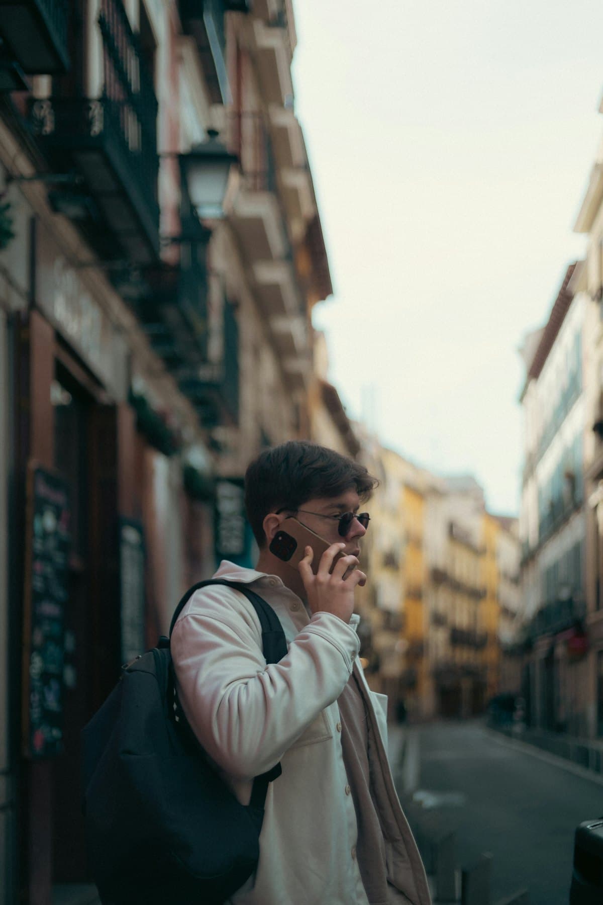 A traveler with a backpack making a phone call on a city street